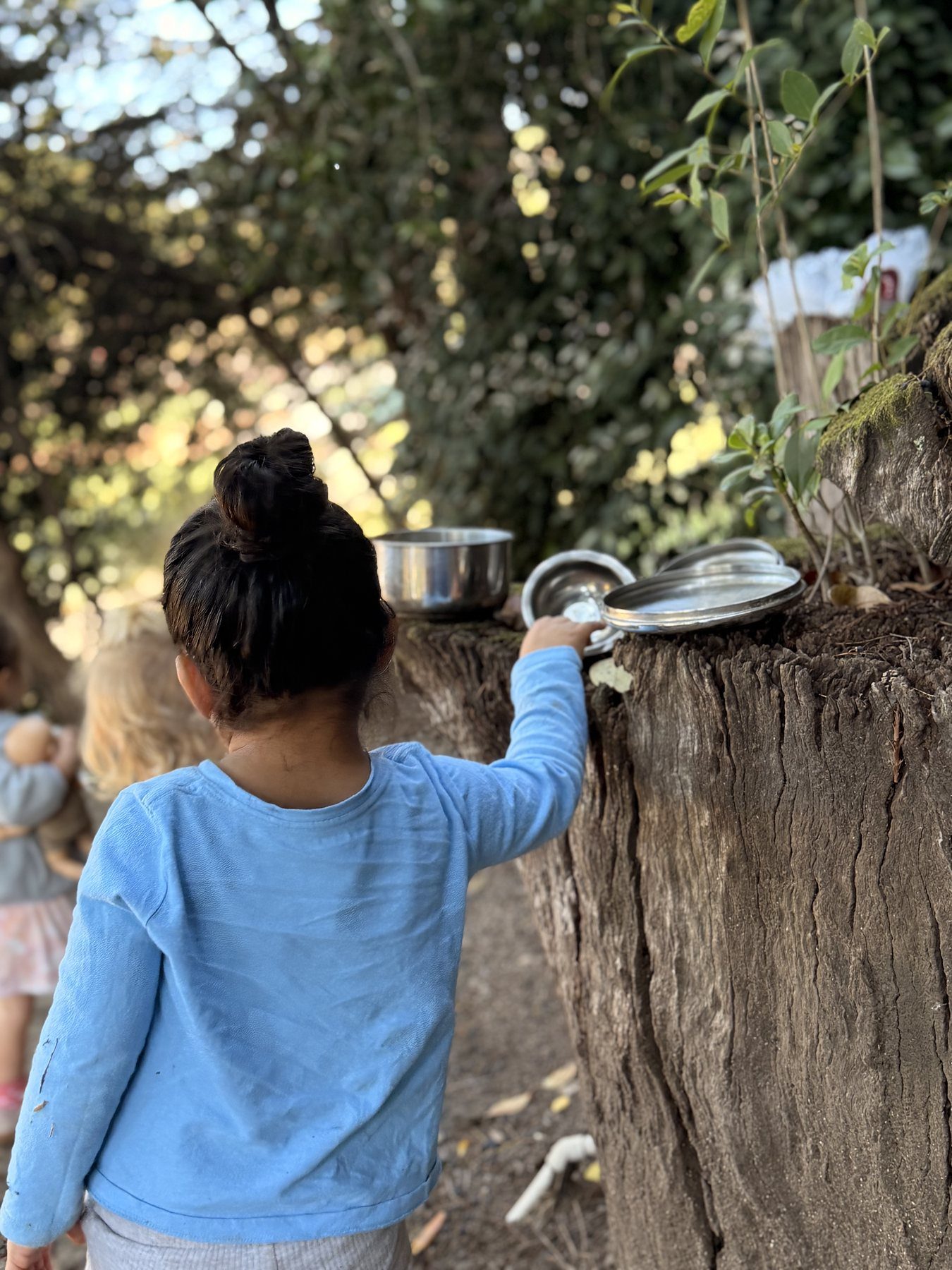 A child engaged in imaginative outdoor play with natural materials
